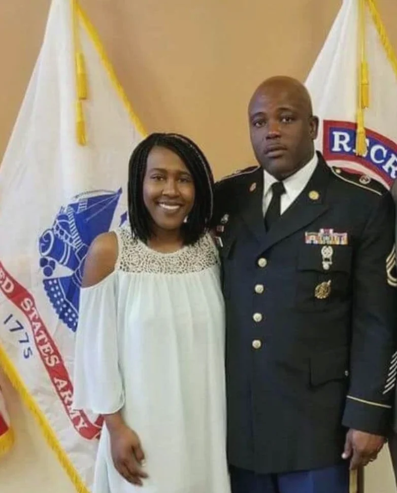 Retired Sergeant First Class Jimmie Lawson in his Army dress uniform, standing beside a woman in a white dress in front of U.S. Army flags.